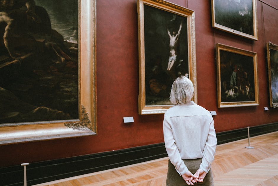A woman observing paintings in a museum, showcasing a back view and an artful ambiance.