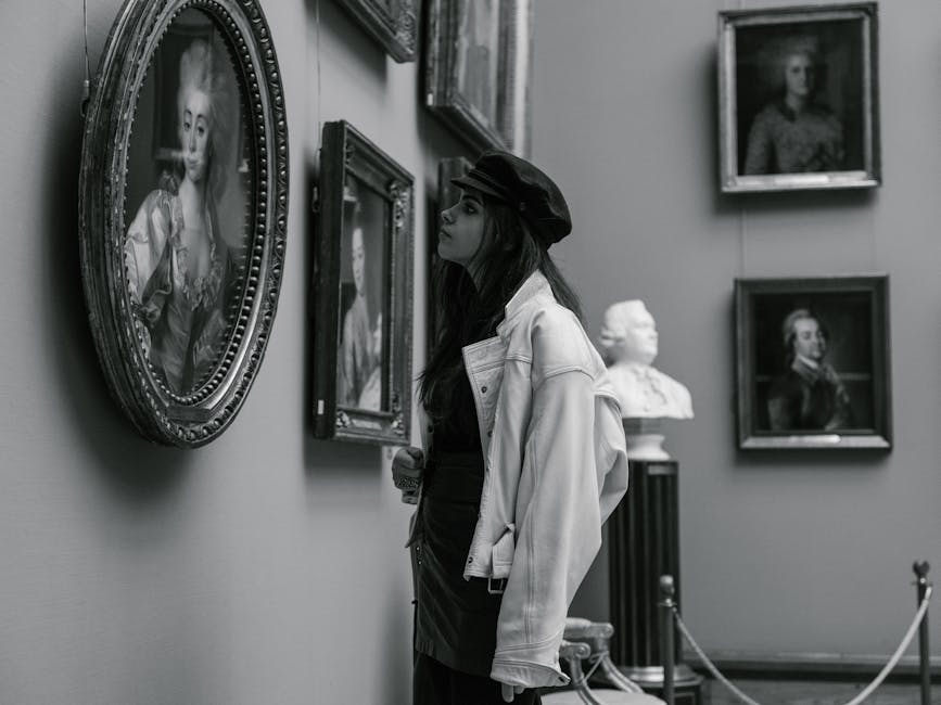Black and white photo of a woman admiring paintings in a museum gallery.